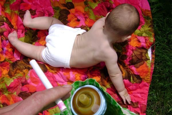 Un bebé jugando sobre una manta de colores al aire libre, en un jardín