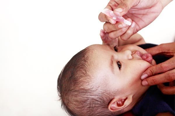 Un bebé recibiendo una vacuna oral de manos de personal de salud